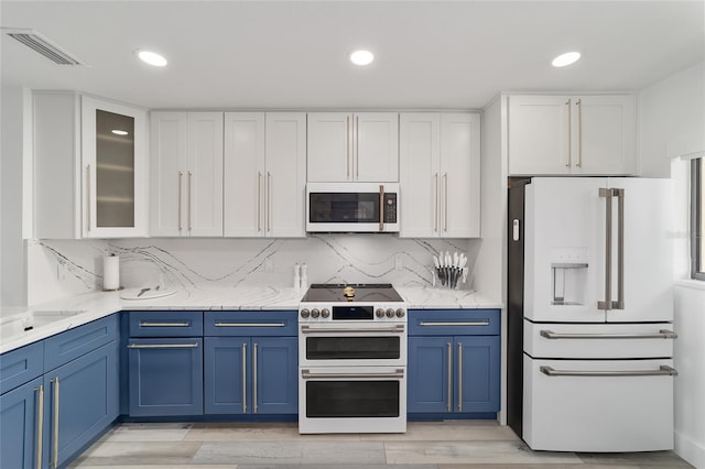 kitchen featuring white cabinets, high quality appliances, light stone counters, and blue cabinetry