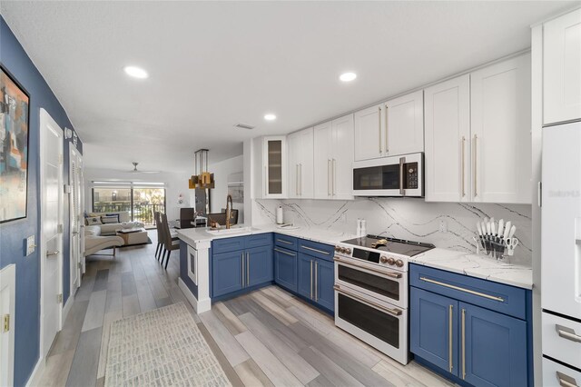 kitchen featuring double oven range, sink, tasteful backsplash, and blue cabinetry