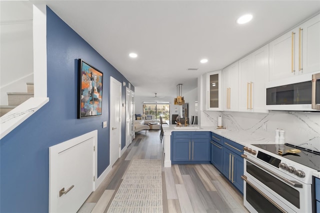 kitchen with tasteful backsplash, blue cabinets, light hardwood / wood-style floors, double oven range, and sink