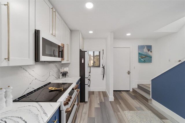 kitchen featuring white cabinetry, tasteful backsplash, stainless steel appliances, light wood-type flooring, and light stone counters