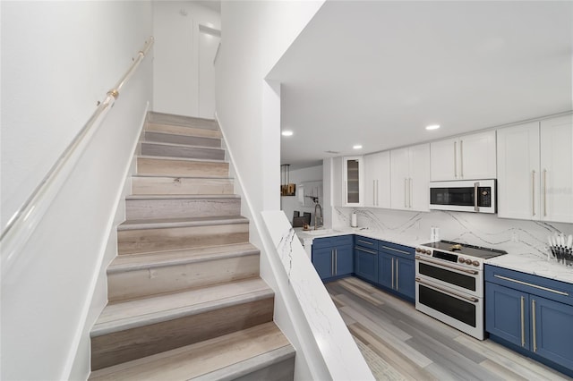 kitchen featuring tasteful backsplash, white cabinets, sink, double oven range, and light hardwood / wood-style flooring