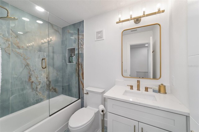 full bathroom with vanity, bath / shower combo with glass door, and toilet