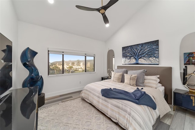 bedroom with light hardwood / wood-style floors, ceiling fan, and high vaulted ceiling