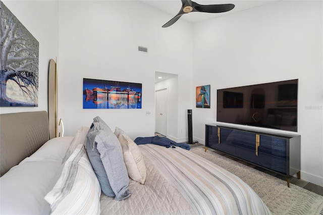 bedroom with hardwood / wood-style flooring, a high ceiling, and ceiling fan