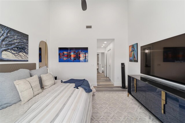 bedroom featuring light hardwood / wood-style flooring and a towering ceiling