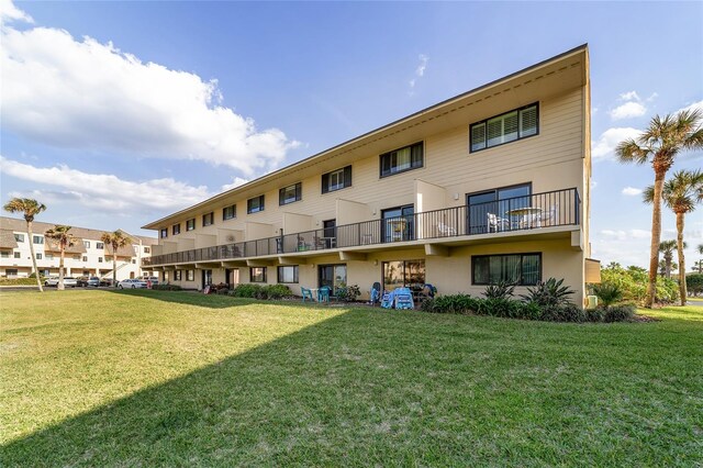 rear view of house with a balcony and a yard