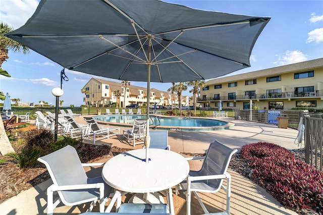 view of patio featuring a balcony and a community pool