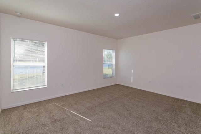 carpeted empty room featuring a textured ceiling