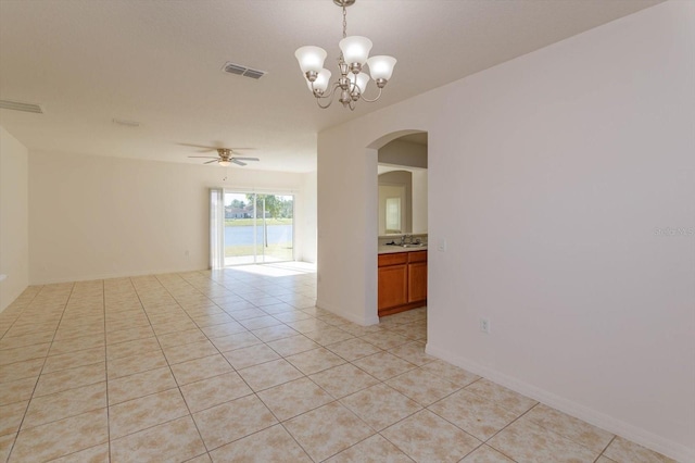 empty room featuring light tile patterned floors, ceiling fan with notable chandelier, and sink