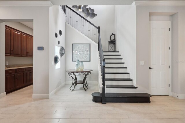 staircase with ornamental molding and light hardwood / wood-style flooring