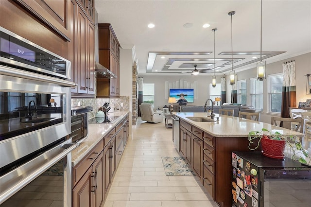 kitchen with appliances with stainless steel finishes, light stone countertops, sink, ceiling fan, and tasteful backsplash