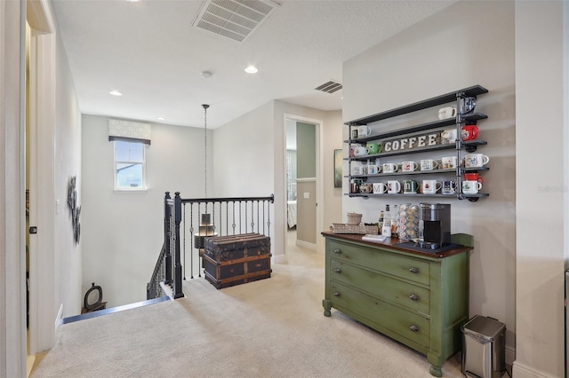 interior space with green cabinetry, pendant lighting, and light carpet