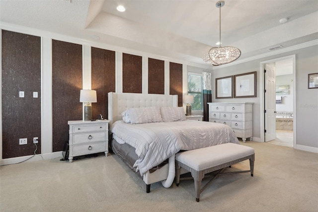 bedroom featuring a chandelier, light colored carpet, ensuite bathroom, and a tray ceiling