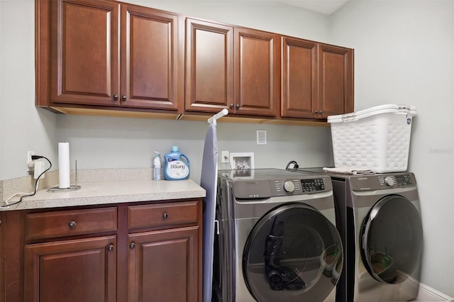 laundry area with washing machine and clothes dryer and cabinets