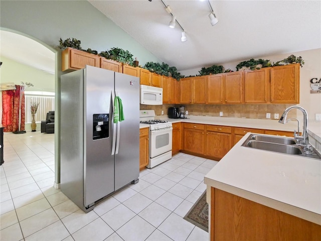 kitchen featuring white appliances, sink, light tile patterned floors, decorative backsplash, and rail lighting