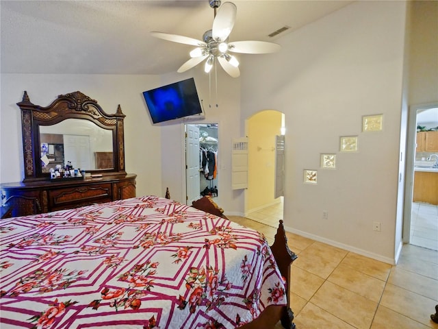 bedroom with a closet, a walk in closet, light tile patterned floors, and ceiling fan