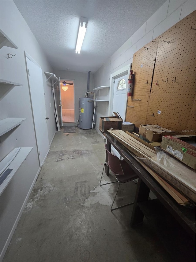 basement with a workshop area, water heater, and a textured ceiling