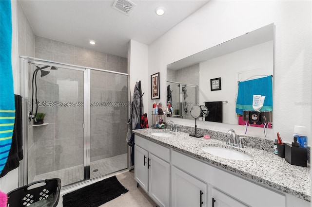 bathroom featuring dual vanity and an enclosed shower