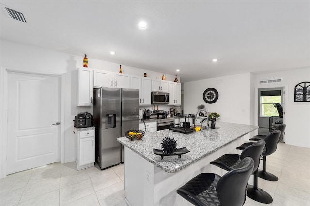 kitchen with light stone counters, white cabinets, stainless steel appliances, and a center island