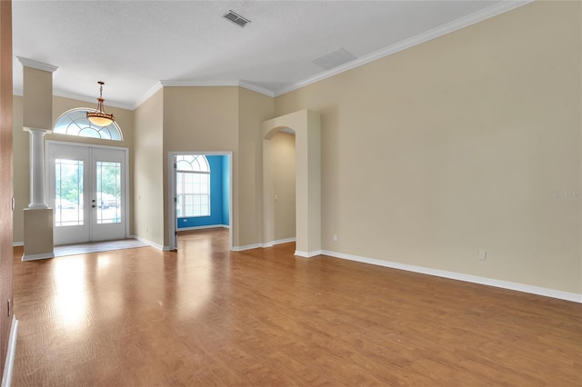 unfurnished living room featuring a textured ceiling, ornamental molding, wood-type flooring, and french doors