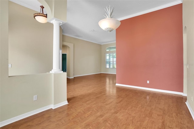 empty room featuring decorative columns, wood-type flooring, and ornamental molding