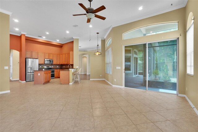 kitchen featuring tasteful backsplash, light tile patterned floors, a center island, ceiling fan, and appliances with stainless steel finishes