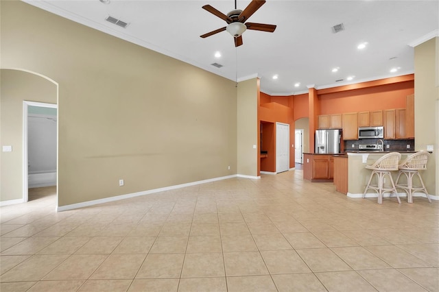 kitchen featuring appliances with stainless steel finishes, light tile patterned floors, decorative backsplash, ceiling fan, and ornamental molding