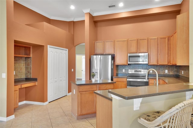 kitchen featuring a breakfast bar area, stainless steel appliances, backsplash, light tile patterned floors, and a kitchen island