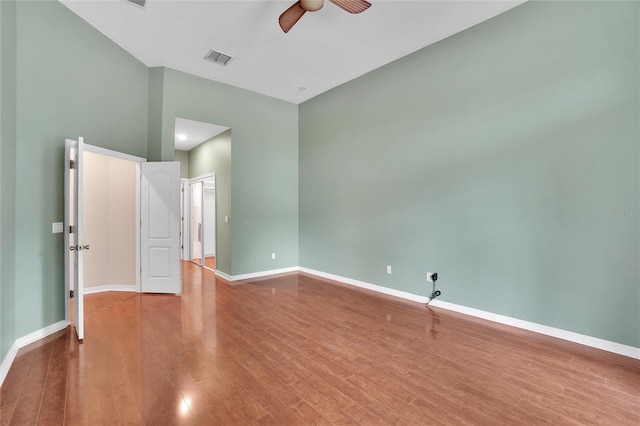 interior space with ceiling fan, hardwood / wood-style flooring, and a towering ceiling