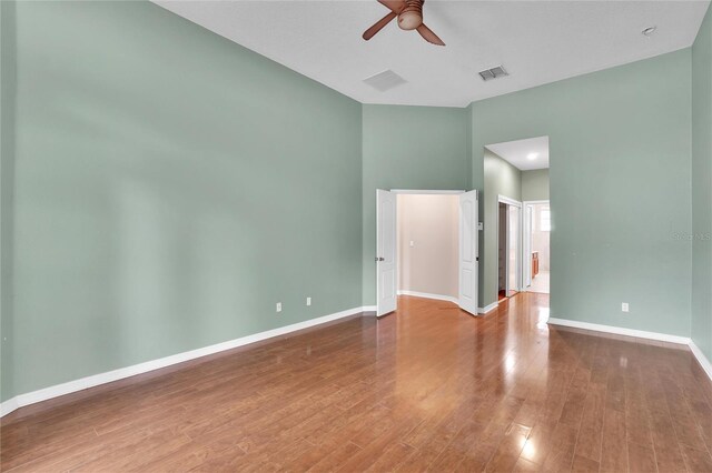 spare room featuring ceiling fan, hardwood / wood-style floors, and a high ceiling