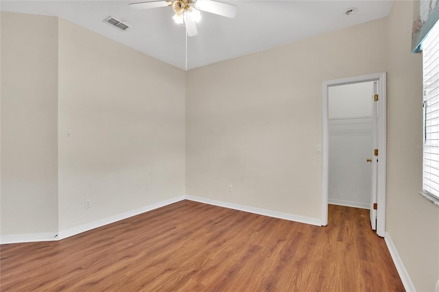 empty room with ceiling fan, wood-type flooring, and a wealth of natural light