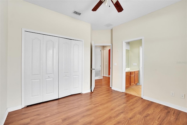 unfurnished bedroom featuring ensuite bath, ceiling fan, a closet, and light tile patterned floors