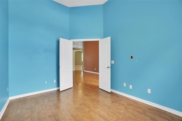 empty room featuring a towering ceiling and hardwood / wood-style floors