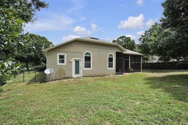 back of property with a sunroom and a lawn