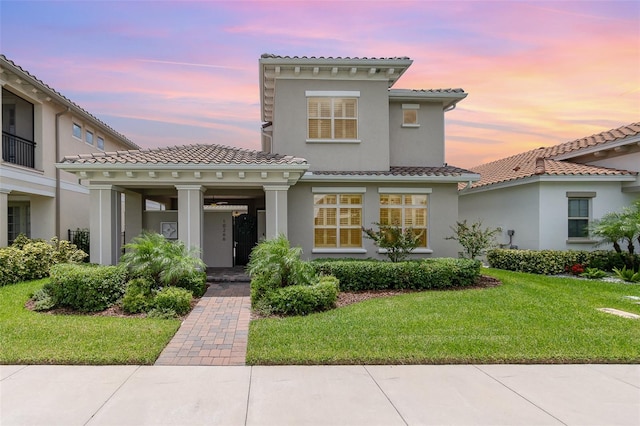 mediterranean / spanish home featuring a tiled roof, a front lawn, and stucco siding