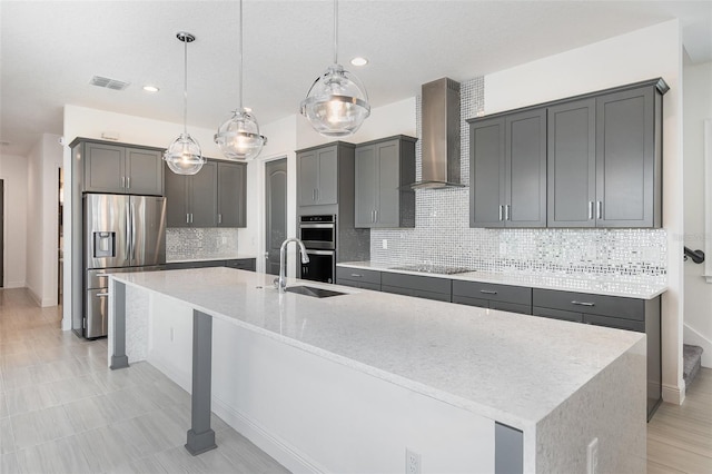 kitchen featuring decorative backsplash, stainless steel appliances, hanging light fixtures, and wall chimney range hood