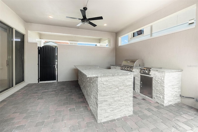 view of patio / terrace with exterior kitchen, ceiling fan, and a grill