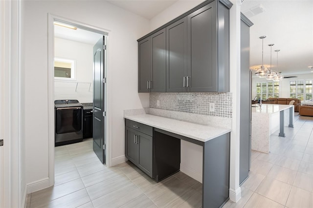 kitchen with washer / clothes dryer, decorative light fixtures, backsplash, and light tile patterned floors