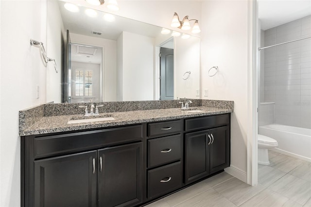 full bathroom featuring tiled shower / bath, vanity, and toilet