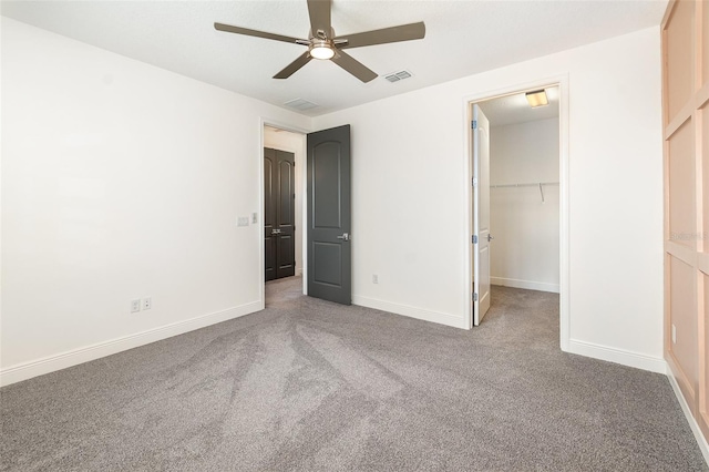 unfurnished bedroom with ceiling fan, a closet, carpet flooring, and a spacious closet