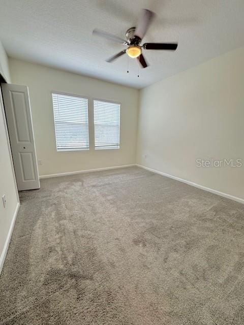 carpeted spare room featuring ceiling fan and a textured ceiling