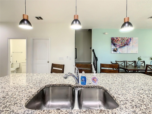 kitchen featuring sink, pendant lighting, and light stone counters