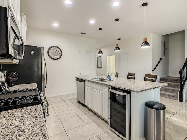 kitchen with wine cooler, sink, white cabinetry, a center island with sink, and appliances with stainless steel finishes