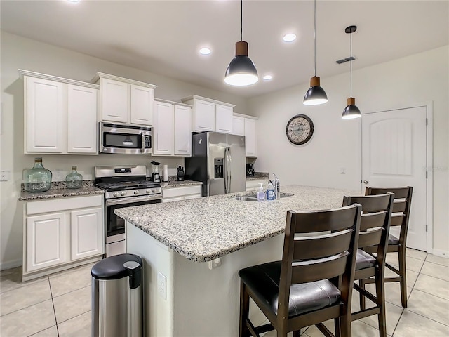 kitchen with white cabinetry, appliances with stainless steel finishes, decorative light fixtures, and an island with sink