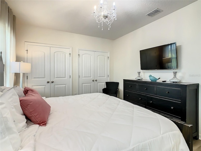 bedroom featuring two closets and an inviting chandelier