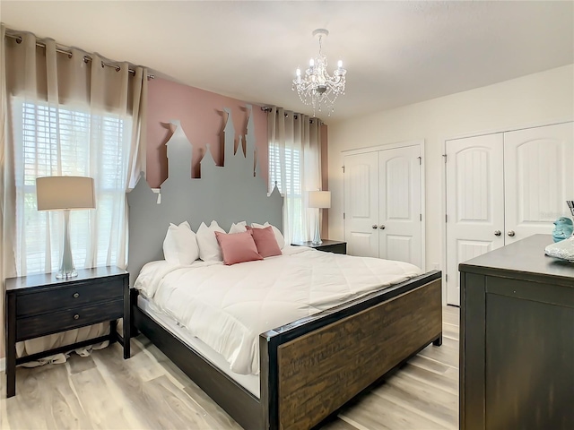 bedroom with a notable chandelier, multiple closets, and light wood-type flooring