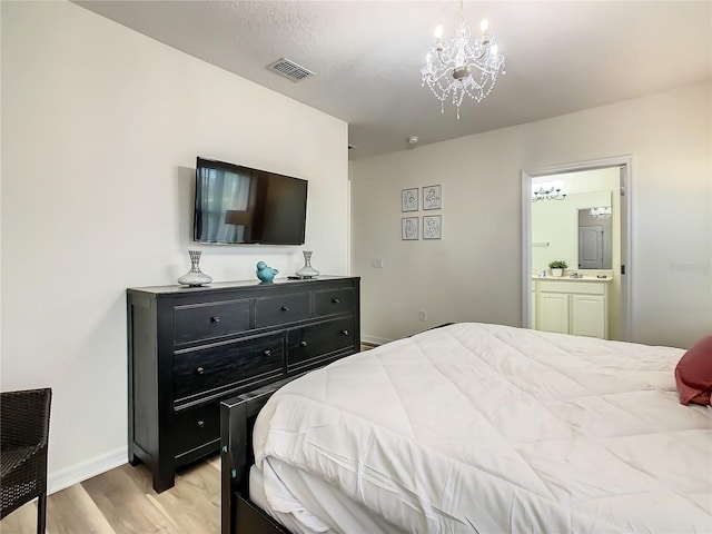 bedroom with ensuite bathroom, a chandelier, and light hardwood / wood-style floors