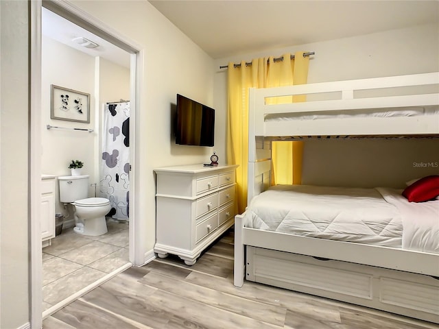 bedroom with connected bathroom and light wood-type flooring