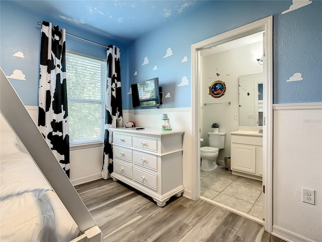 bedroom featuring connected bathroom and light wood-type flooring