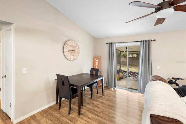 dining area featuring lofted ceiling, light wood-type flooring, a textured ceiling, and ceiling fan